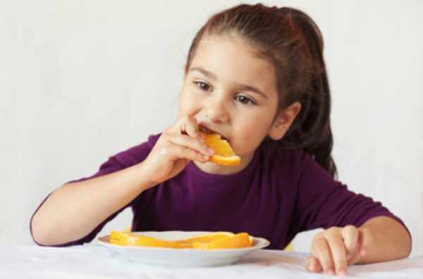 Девочка ест нарезанный апельсин