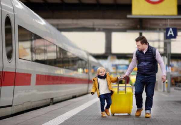Ребенок с папой тянут чемодан на платформе возле поезда