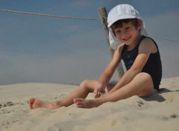 Мальчик в панамке сидит на песке