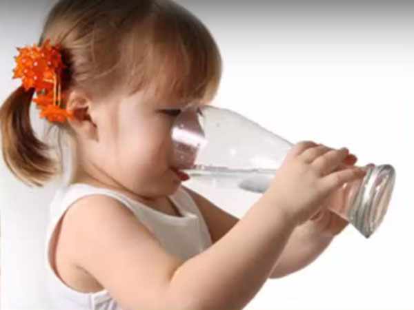 Девочка пьет воду из большого бокала