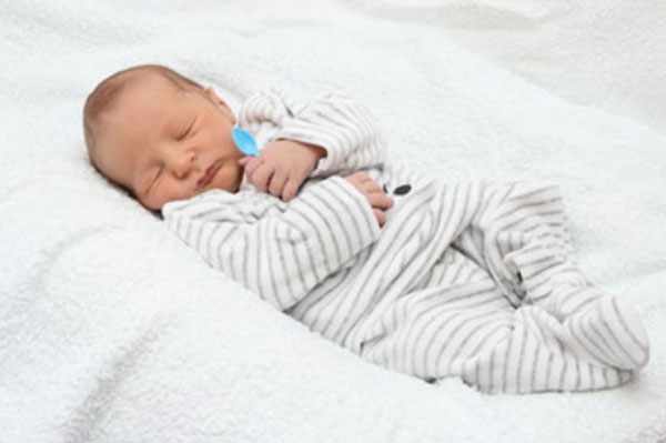 Новорожденный ребенок сладко спит, сжимая в своей ручке чайную ложечку