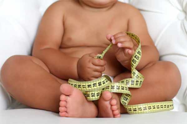 Ребенок с ожирением держит в руках сантиметровую ленту