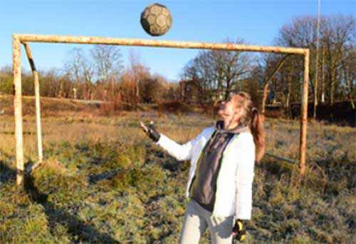Девочка с мячом возле футбольных ворот