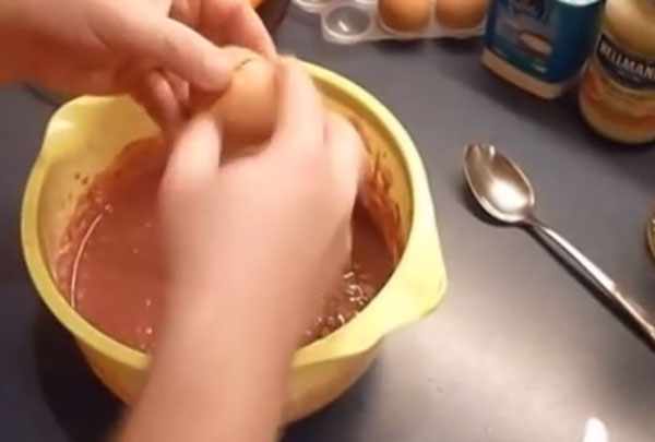 Разбивание яйца над миской с печеночной массой