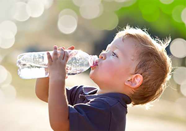 Мальчик пьет воду из бутылки