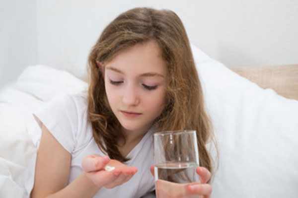 Девочка со стаканом воды, собирается выпить таблетку