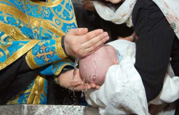 Священнослужитель поливает голову ребенка