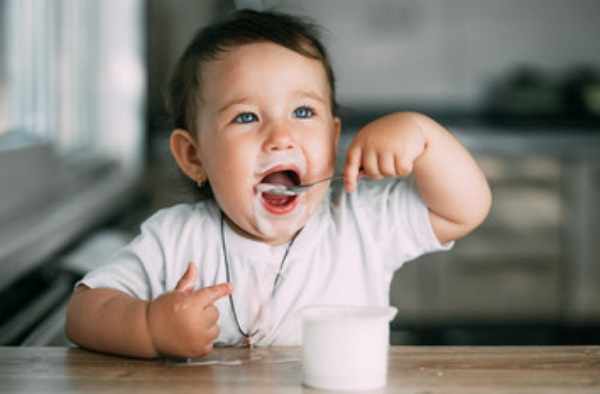 Ребенок самостоятельно кушает йогурт