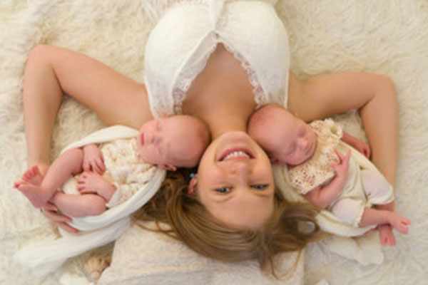 Счастливая женщина лежит посередине между двух близнецов