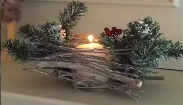 Зажженная свеча в самодельном горшке, украшенном елочными ветвями