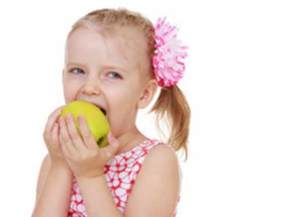 Девочка кусает желто-зеленое яблоко
