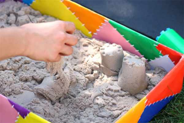 Кинетический песок лежит в декорированной песочнице