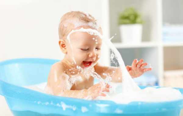 Ребенок сидит в ванночке и плескается в воде