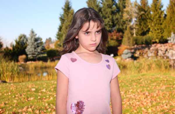 Сердитая девочка стоит на поляне