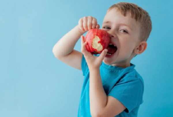 Мальчик держит в руке надкусанное яблоко