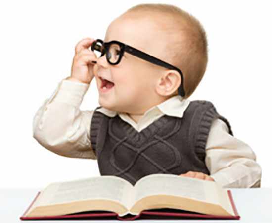 Маленький ребенок в очках сидит перед открытой книгой