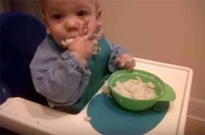 Ребенок ест руками овсянку