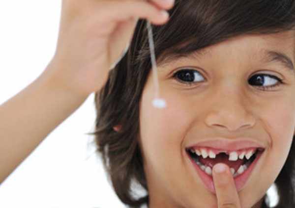 Мальчик на нитке держит свой вырванный зуб