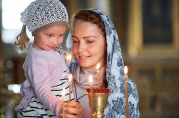 Мама с дочкой в церкви. Ставят зажженную свечу