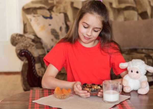 Девочка смотрит на тарелку с сухофруктами