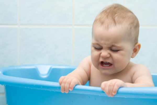 Ребенок сидит в ванночке и плачет