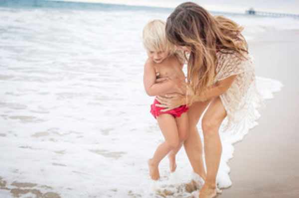 Мама стоит с ребенком у самого берега, вода покрывает ноги