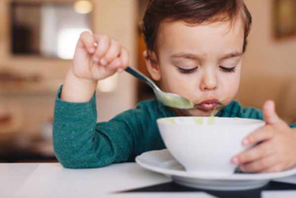 Маленький мальчик ест овощной суп