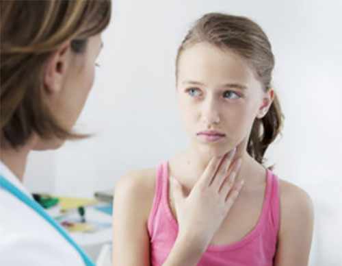 Девочка стоит возле врача и держится рукой за горло