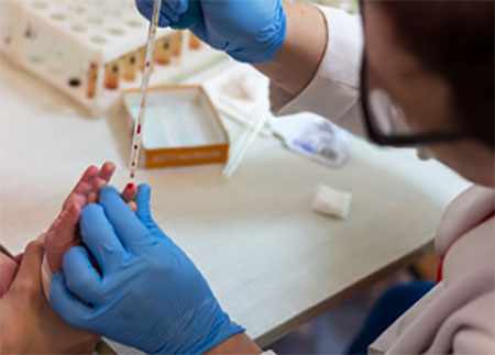 Лаборант берет кровь из пальца ребенка