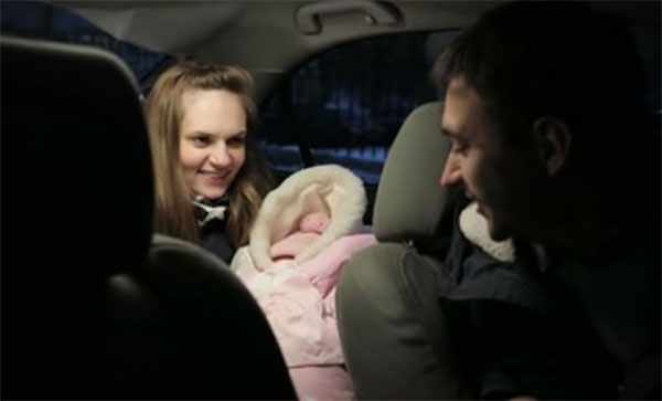 В салоне автомобиля мама с новорожденным, завернутым в конверт и водитель