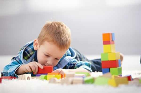 Мальчик играет разноцветными деревянными кубиками