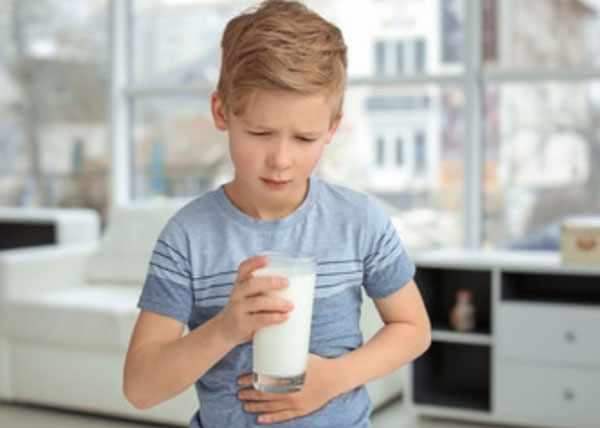 Мальчик со стаканом молока держится за живот