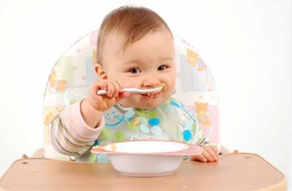 Маленький ребенок сам кушает с ложечки