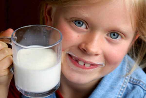 Девочка с молочными усами и чашкой молока в руках