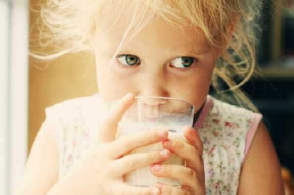 Девочка пьет молоко со стакана