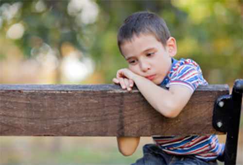 Одинокий, грустный мальчик сидит на скамейке