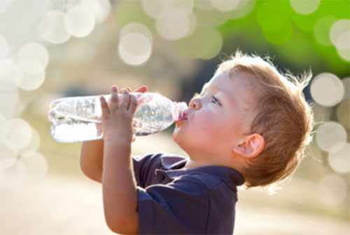 Мальчик пьет воду с бутылки